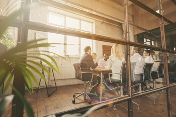 Nice attractive focused stylish skilled executive managers gathering discussing sales marketing industry plan result at loft industrial style interior workplace workstation behind glass wall