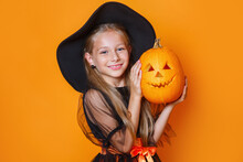 Happy Child Girl In Witch Costume Holding Pumpkin