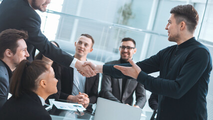 Wall Mural - smiling business people shaking hands over an office Desk