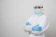 © Chanakon - A portrait of virologist Wearing PPE suit cross his arm and look back into camera isolated on white background. Personal Protective Equipment Concept.