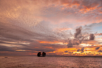 Beautiful tropical sunset over the sea horizon with vibrant color with silhouette of island