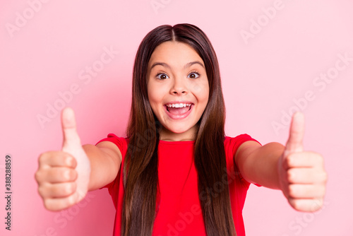 Photo of lovely cute funky little lady long hairstyle raise two hands presenting showing thumb ups open mouth excited crazy look smile wear red t-shirt isolated pink color background