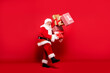 © neonshot - Santa Claus with a lot of gifts on a red background.