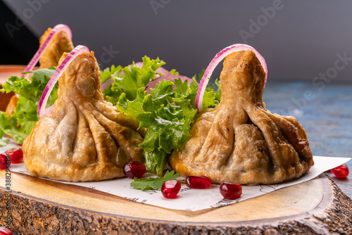 Fotografía Georgian deep-fried Khinkali dumplings with meat and red pepper, on a wooden cutting board