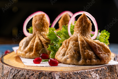 Cuadros en Lienzo Georgian deep-fried Khinkali dumplings with meat and red pepper, on a wooden cutting board