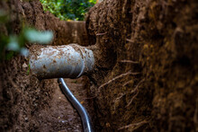 Sewer And Water Pipe In An Excavated Trench Deep In The Ground, Close Up. Sewerage And Water System Repair Concept.