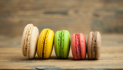 Poster - Colorful macaroons, delicious French pastries, stacked on wooden table.