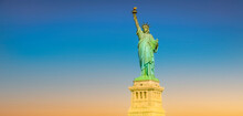 Statue Of Liberty In New York, USA. Blue Sky And Warm Sunset Panoramic Background With Copy Space