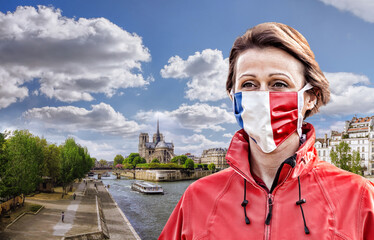 Fototapete - Woman wearing protection face mask with French flag against coronavirus near the Notre Dame cathedral with sunrise in France