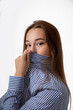 © Татьяна Волкова - Young woman covers her nose and mouth with a shirt instead of a mask for fear of bacteria and the COVID-19 virus
