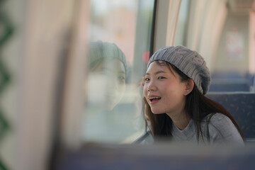 Poster - lifestyle portrait of young happy and beautiful Asian Japanese woman excited and cheerful looking through window sitting on train enjoying landscape from the railcar glass