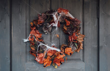 Colorful Wreath For Halloween Hanging On Wooden House Door Made Of Old Orange Maple Leaves.Spider Web.Decorating Of Porch.Home, Outdoort,street Decoration,entertainment For Children,horror Atmosphere