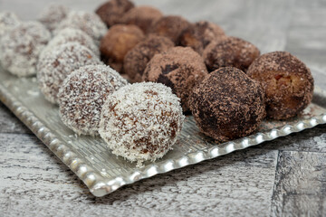 Coconut rum balls being covered with grated coconut on plate