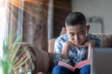 Wall Mural - Boy praying on sofa with bible, Home church during quarantine coronavirus Covid-19, Religion concept.