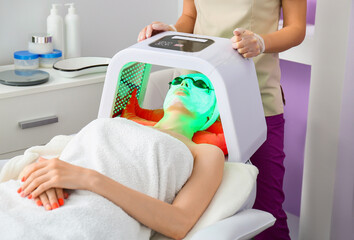 Woman undergoing procedure of facial chromotherapy in beauty salon