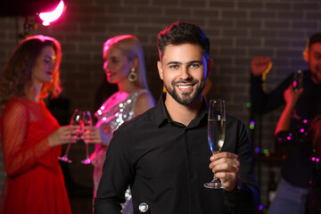 Canvas Print - Young man with glass of tasty champagne at party in nightclub