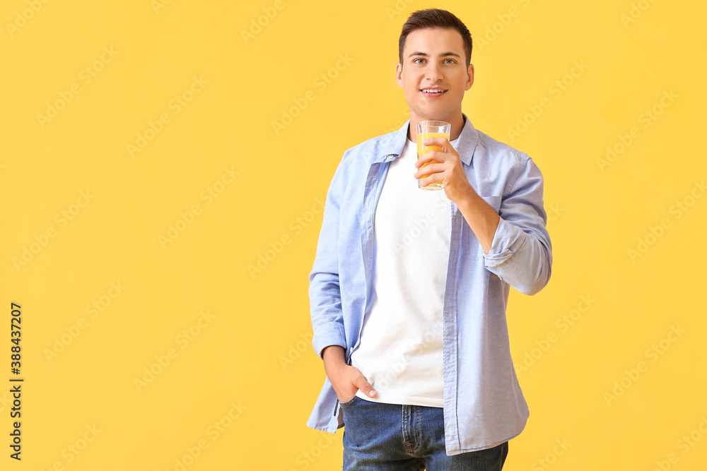 Handsome man with orange juice on color background