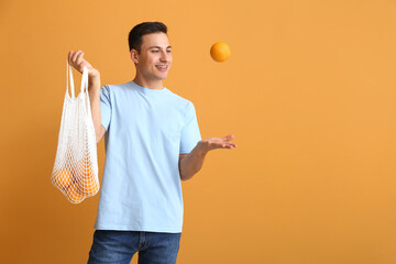 Poster - Handsome man with ripe oranges on color background