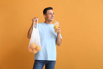 Poster - Handsome man with ripe oranges and juice on color background