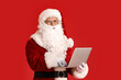 © Pixel-Shot - Santa Claus with laptop on color background
