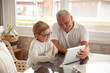 © Iryna Dincer - Happy family senior and little boy using tablet for conversation with their relatives or friends, waving hands and say Hello. Grandson and grandfather having video chat using tablet.