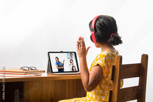 Indian girl studying using laptop or tablet during home schooling - online learning concept