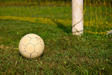 Soccer ball lying on the green grass beside the soccer goal