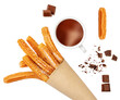 Creative layout made of Churros fried pastry, cup of dark chocolate and chocolate pieces  isolated on a white background, top view. Flat lay.