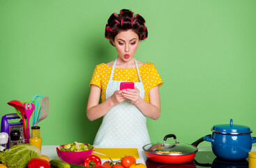 Sticker - Photo of shocked girl prepare fresh dish use smartphone choose recipe table with pepper salad tomato wear yellow dotted t-shirt hair rollers isolated green color background