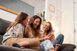 © CarlosBarquero - Group of female friends on the sofa at home, using a mobile phone laughing.