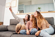 © CarlosBarquero - Group of female friends on the sofa at home taking a selfie.