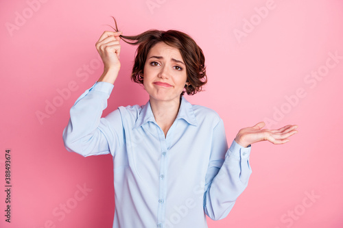 Whatever. Photo of attractive sad lady hold hairdo curl see split dry damaged ends condition after shampoo awful result shrug shoulders wear blue shirt isolated pink pastel color background