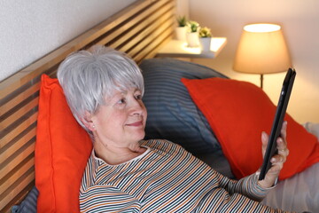 Senior woman using table in bed at night