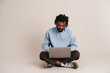 © Drobot Dean - Serious african american guy working with laptop while sitting on floor