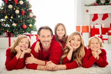 Poster - Photo of full big family five people meeting three little kids cuddle hold hand cheeks lie floor carpet toothy smile wear red jumper in living room x-mas tree lights giftboxes indoors