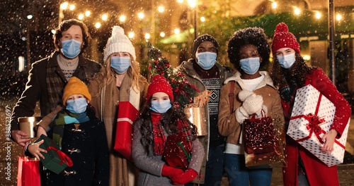 Fotomural Portrait of happy mixed-races people with presents on street while snowing and smiling