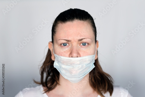 Young woman demonstrates the wrong way to wear a mask to avoid the spread of coronavirus Covid-19,  with the nose out of the mask