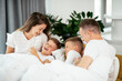 © JustLife - Young family enjoying in bed. Happy parents with sons relaxing in bed.