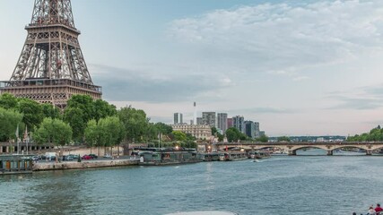 Sticker - Eiffel tower and Jena bridge over Seine river evening timelapse from waterfront, Paris, France. Ship on the river and reflections in water