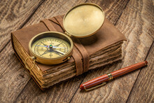 Retro Leather-bound Journal With Decked Edge Handmade Paper Pages, Antique Brass Compass And A Stylish Pen On A Rustic Wooden Table, Journaling Concept