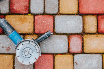 Wall Mural - Electric circular saw grinder against the background of stone paving stones - diamond disc for stone and porcelain stoneware