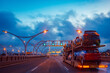 © Grispb - Car transporter with passenger cars. An auto transporter drives along an empty road. Cargo truck transports cars. Car transporter drives through the evening city