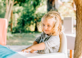 Wall Mural - Girl sitting in high chair and smiling