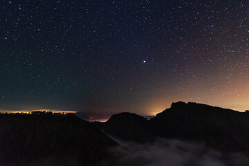 Wall Mural - A beautiful starry night in the mountains on top with beautiful scenery and fog.