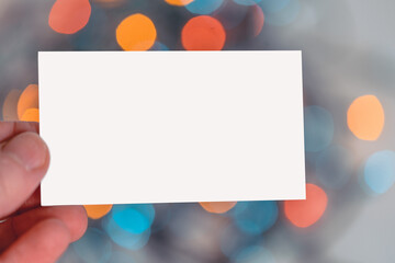 Blank White Business Card Hold By Man Hand on Christmas Garland Background. Festive Mood And Vibes