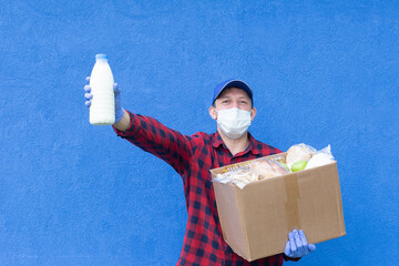 Wall Mural - volunteer with a box of food on a blue background, donations