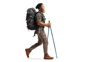 full length profile shot of a bearded man with a backpack and hiking poles walking