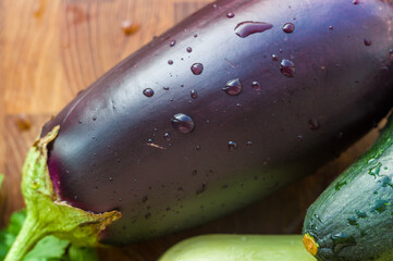 Still life - fresh whole zucchini, eggplant and parsley on a wooden board, close up