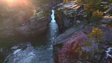 Wall Mural - Fast moving water falls and rapids of a glacial river at sunset. 4K aerial video.