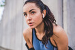© InsideCreativeHouse - Close up shot of young pretty caucasian female athlete resting after jogging with earbuds against grey wall
